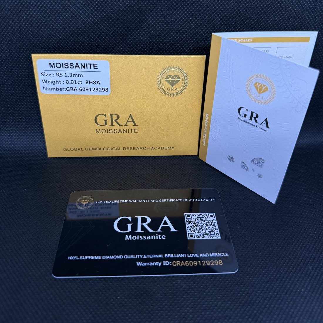 A GRA moissanite certificate envelope, warranty card with QR code, and printed report